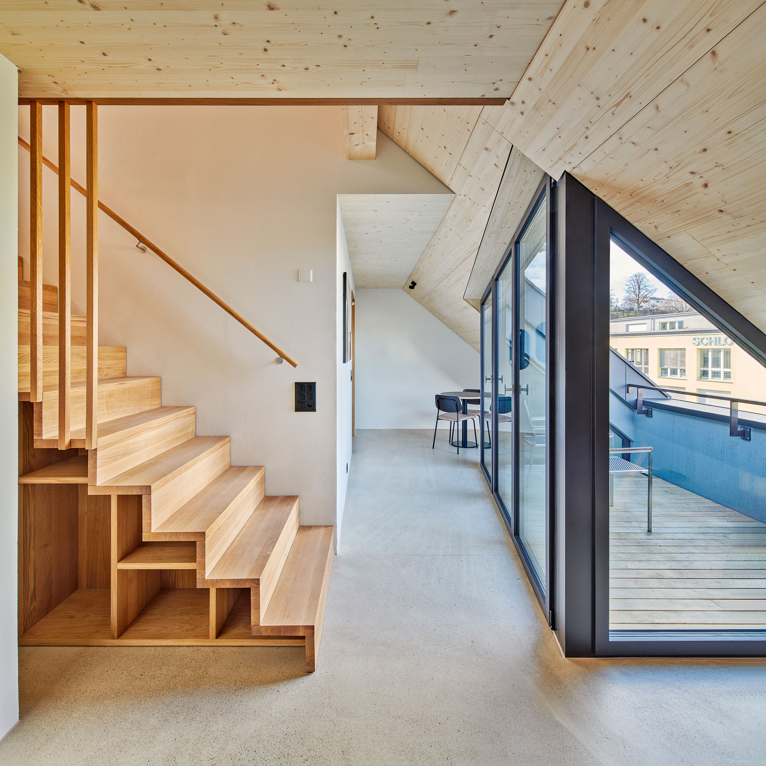 heller Wohnraum im dachgeschoss Wohnung mit Loggia, Holzbau und Holztreppe mit sichtbarem Unterlagsboden