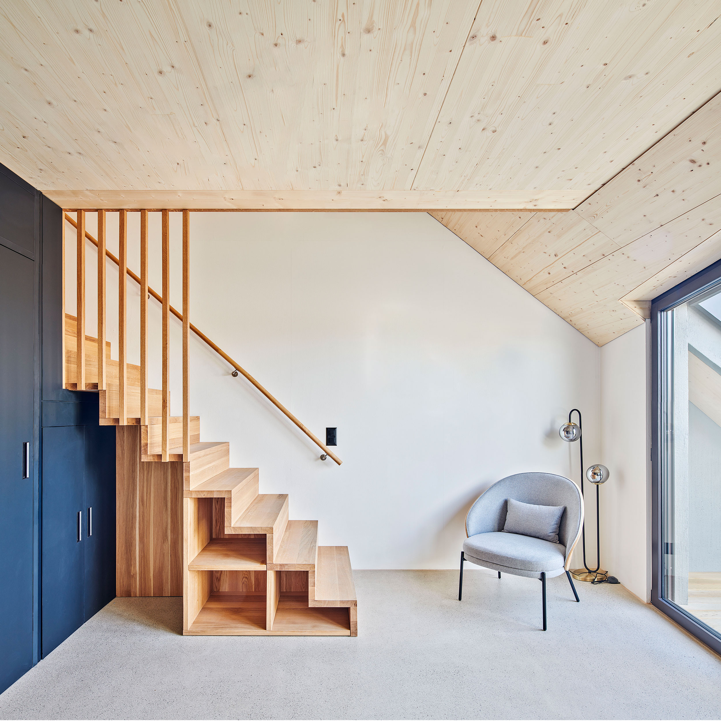 heller Wohnraum im dachgeschoss Wohnung mit Loggia, Holzbau und Holztreppe mit sichtbarem Unterlagsboden