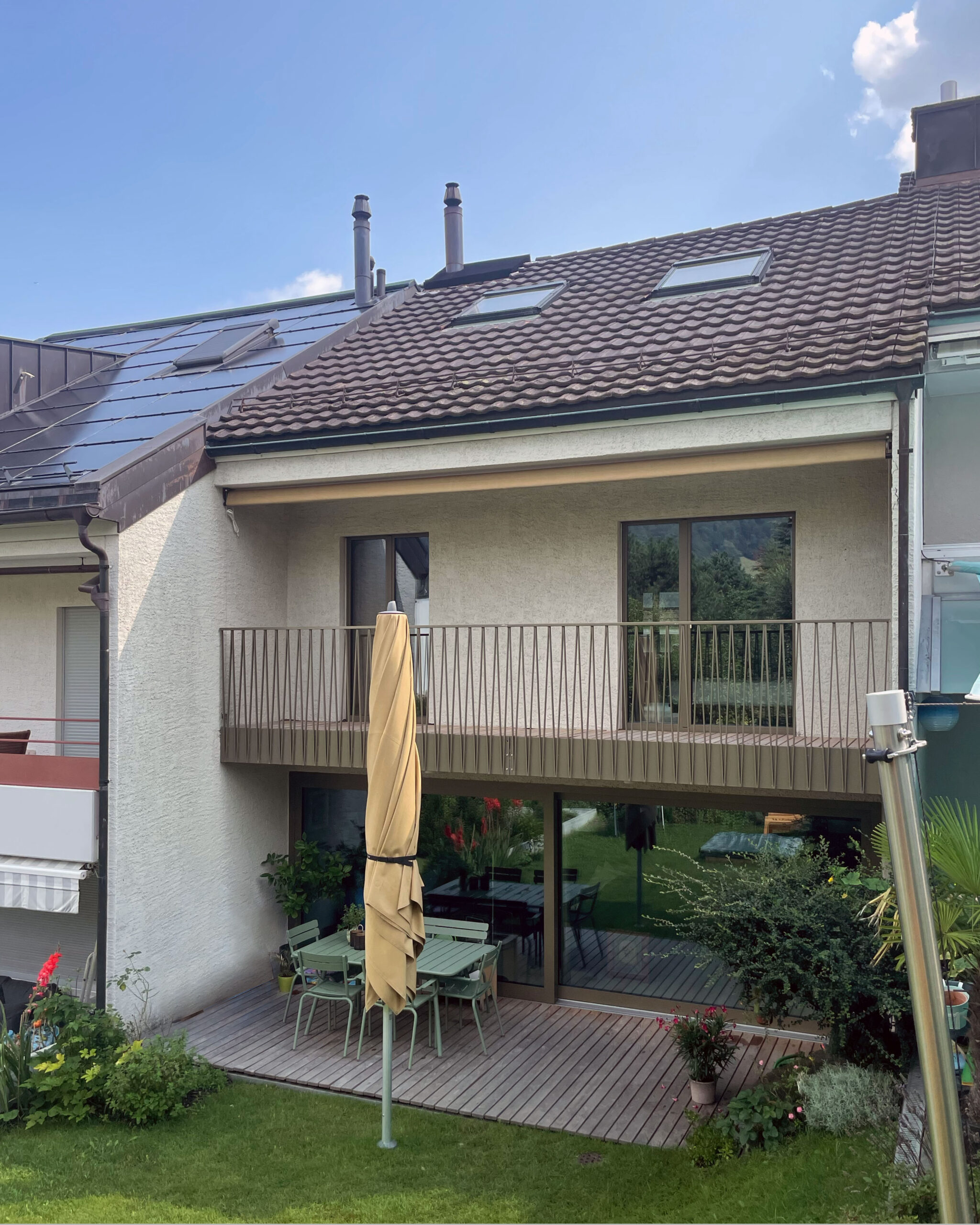 Helles Ankleidezimmer mit Blick nach draussen auf den Balkon, Holzboden, Holzmöbel und gelbe Fensterrahmen