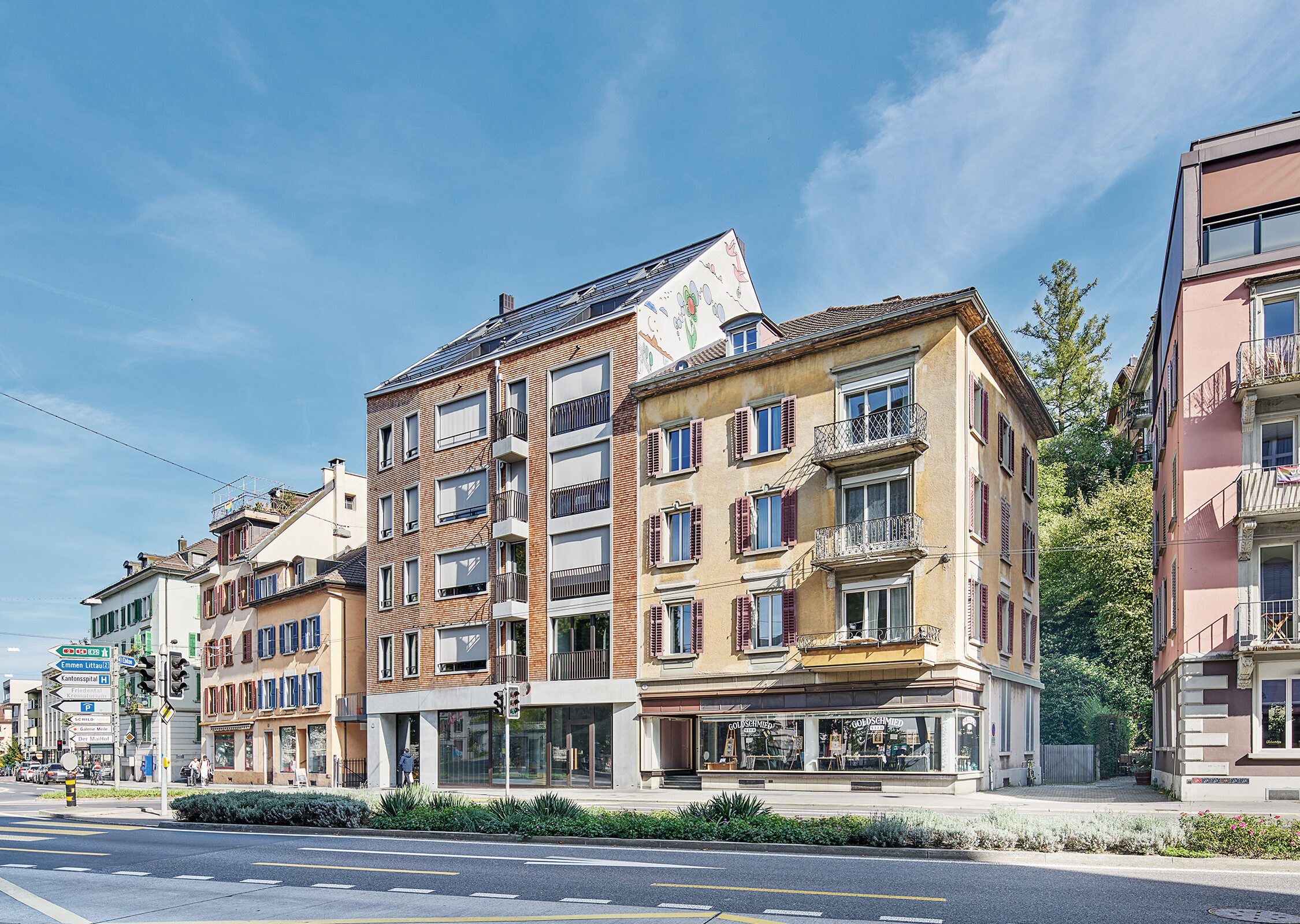 6 Stöckiges Mehrfamilienhaus mit Holzschindeln, grossen Fensterflächen und Betonelementen, im urbanen Kontext