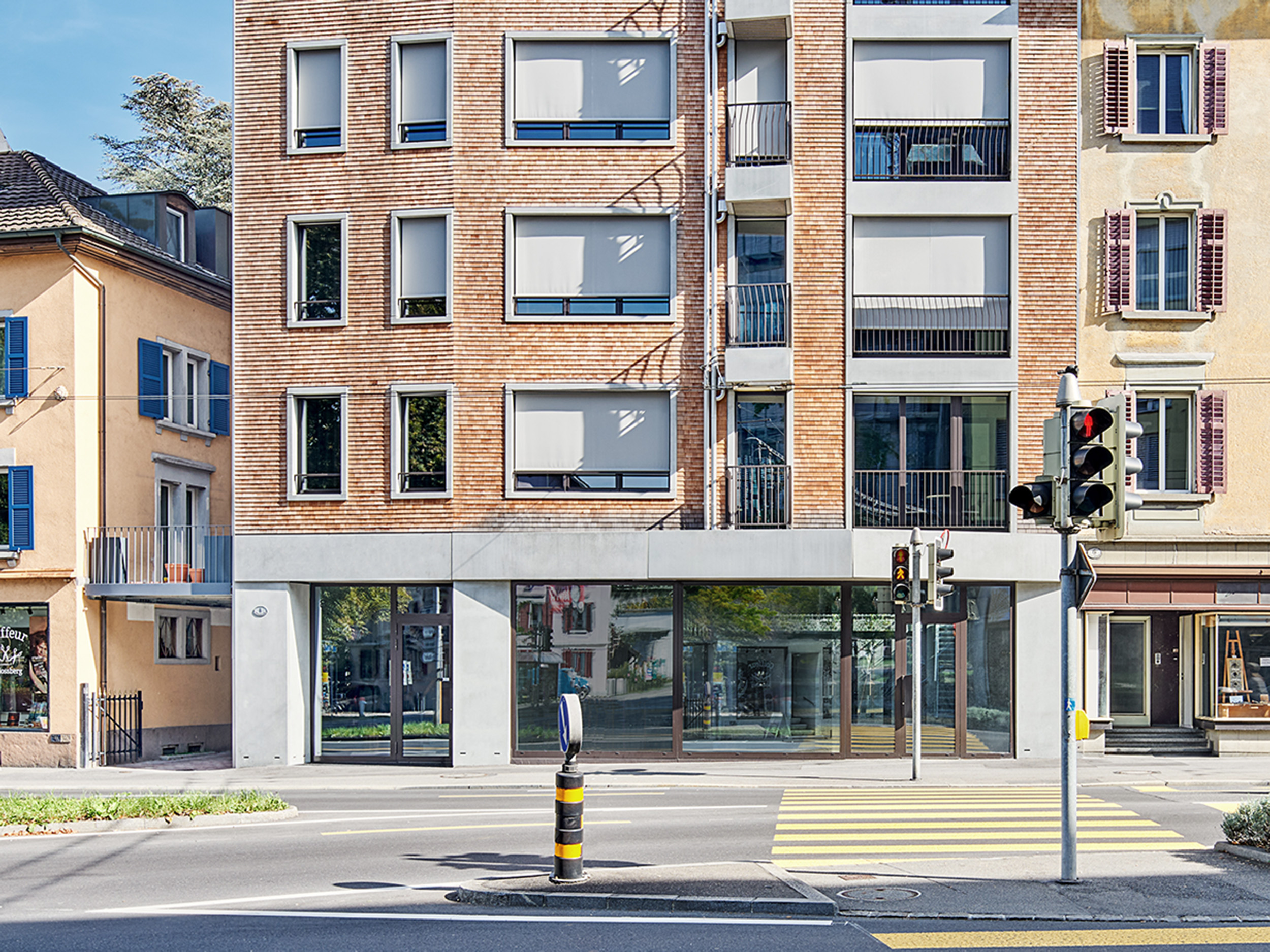 Fassade des Neubaus mit Holzschindeln, grossen Fensterflächen mit Betonelementen im Erdgeschoss, and den Balkonen und an den Fenstern